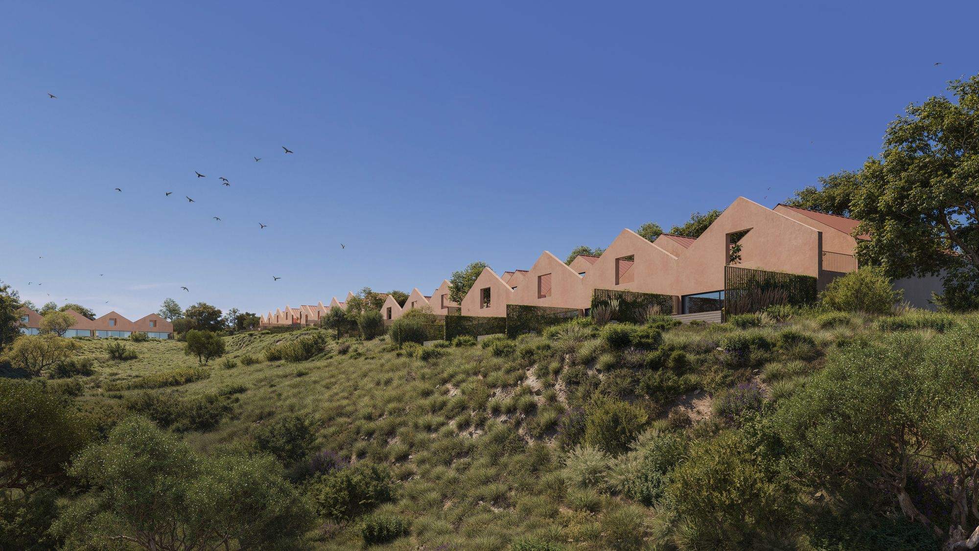 The village of Vila Alba: a row of townhouses in warm terracotta plaster with pitched roofs along a green hillside under a blue sky